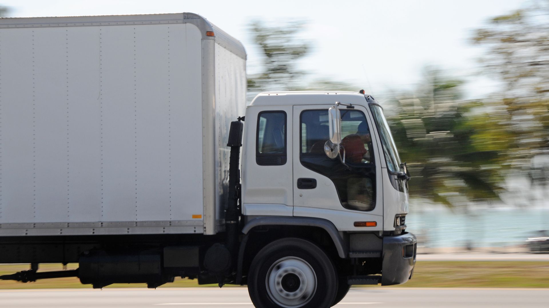White delivery truck driving on road with blurred background