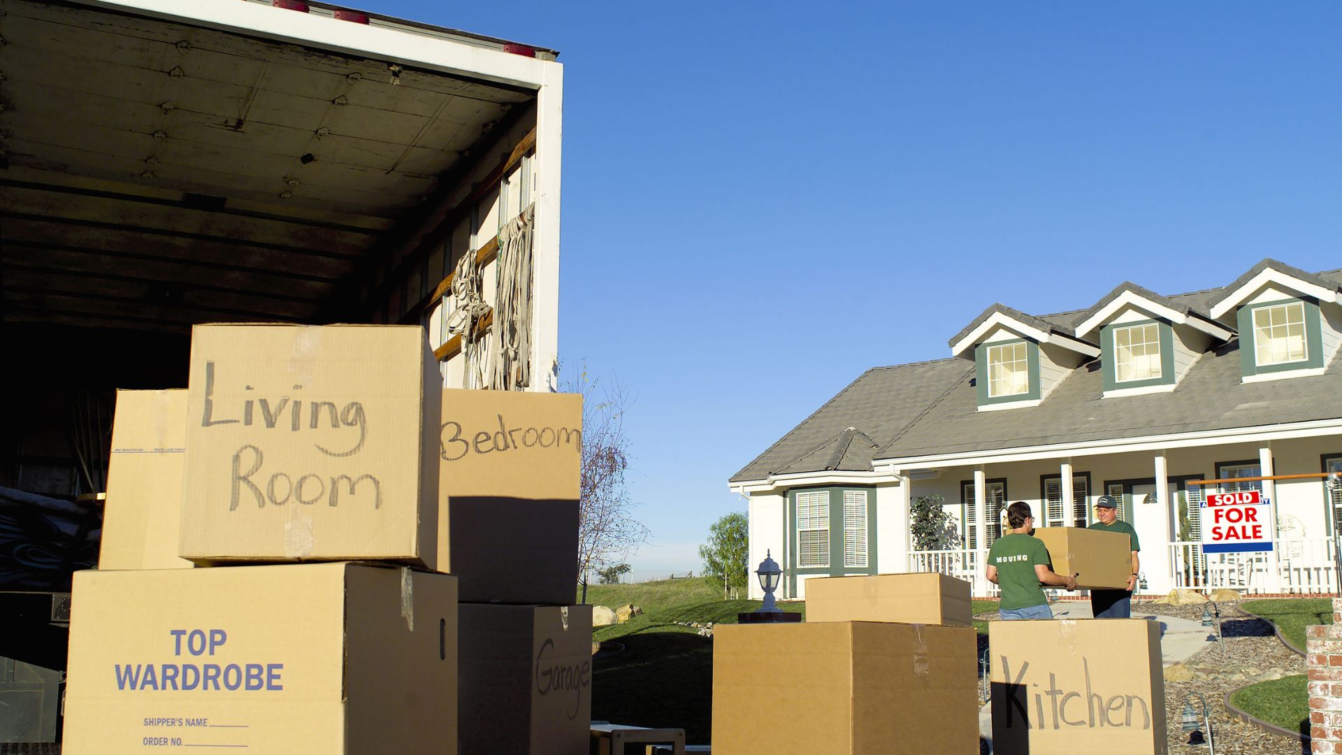 Moving day with labeled boxes in front of a house with a sold sign