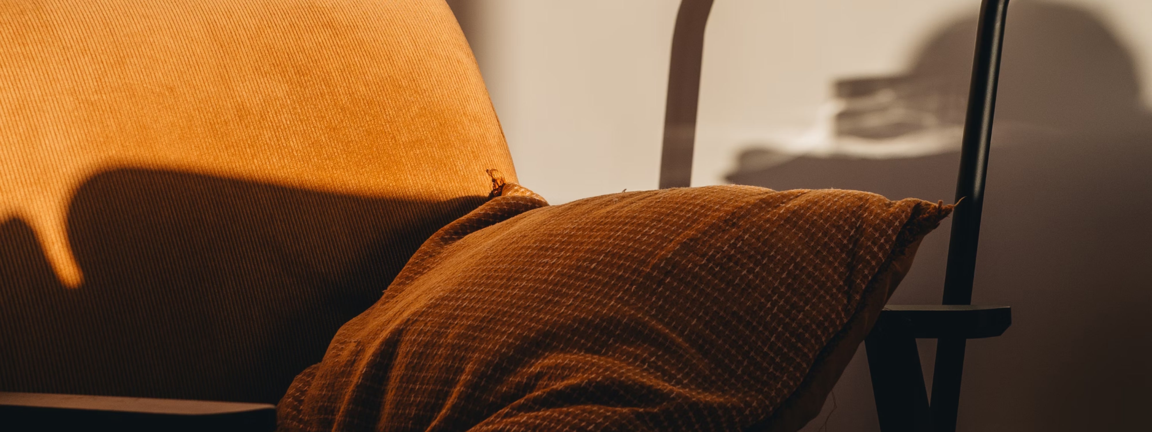 Warm orange and brown textured cushions on a chair with soft shadows