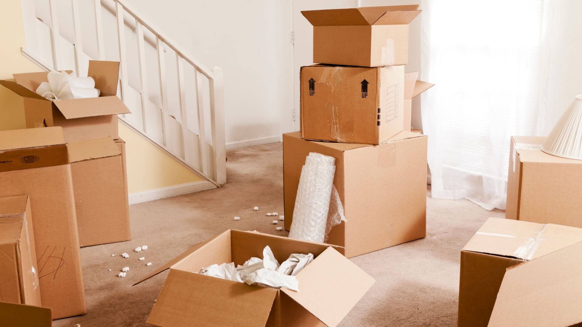 Moving day with cardboard boxes scattered near staircase and packed items